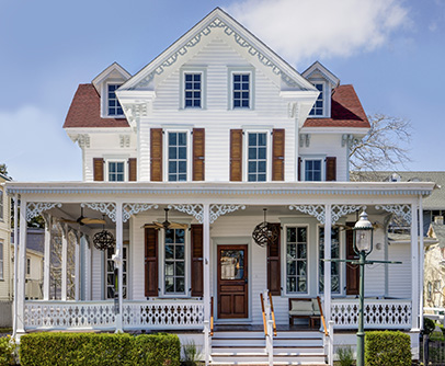 White Victorian home with plae blue gingerbread and brown shutters