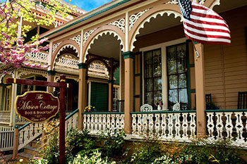 An exterior shot of the Mason Cottage's porch in summer with an American flag waving