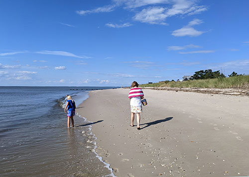 A family walking along the Delaware Bay beach in Villas, NJ
