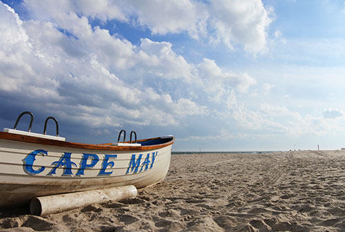 Cape May lifeguard boat on the beach under a cloudy blue sky