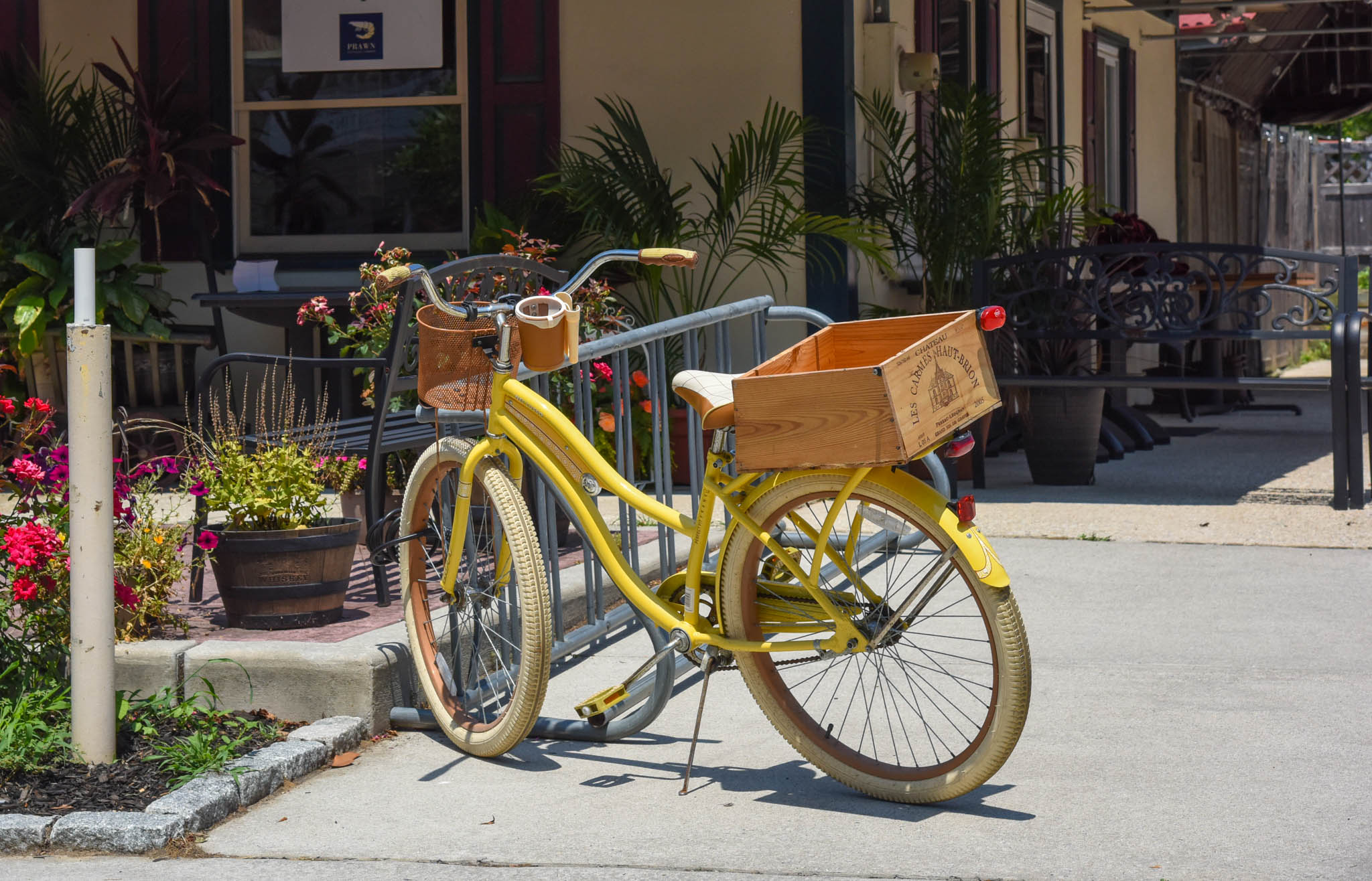 Yellow bicycle with wooden basket parked outside of a takeout restaurant