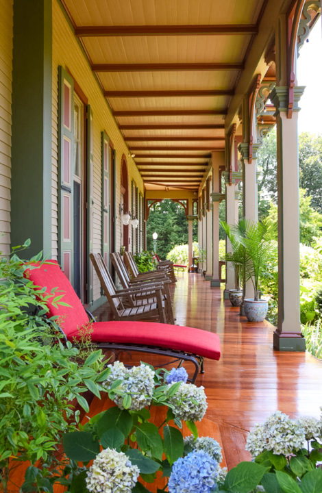 Red lounge chair on the porch at the Southern Mansion, blue hydrangeas in the foreground