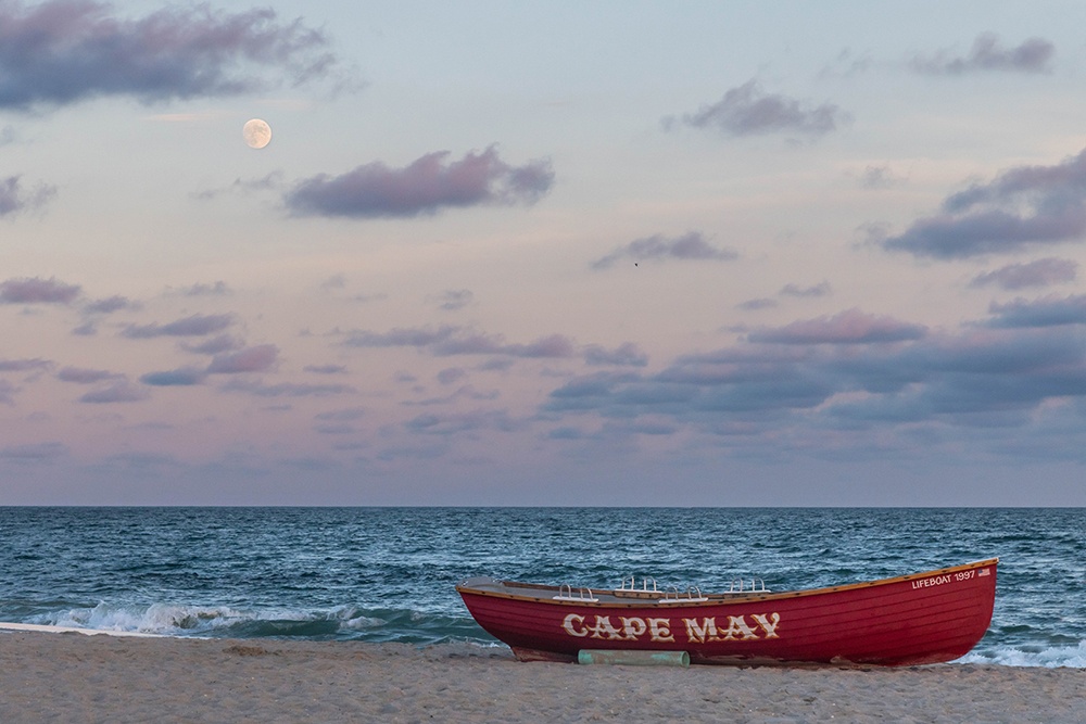 Moon rising over the ocean, beach, and Cape May lifeguard boat.