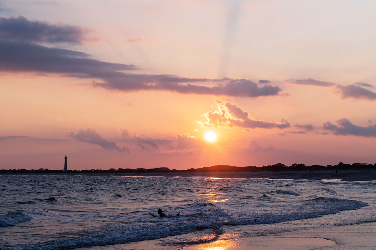 Sunset with clouds at the horizon and someone swimming in the ocean