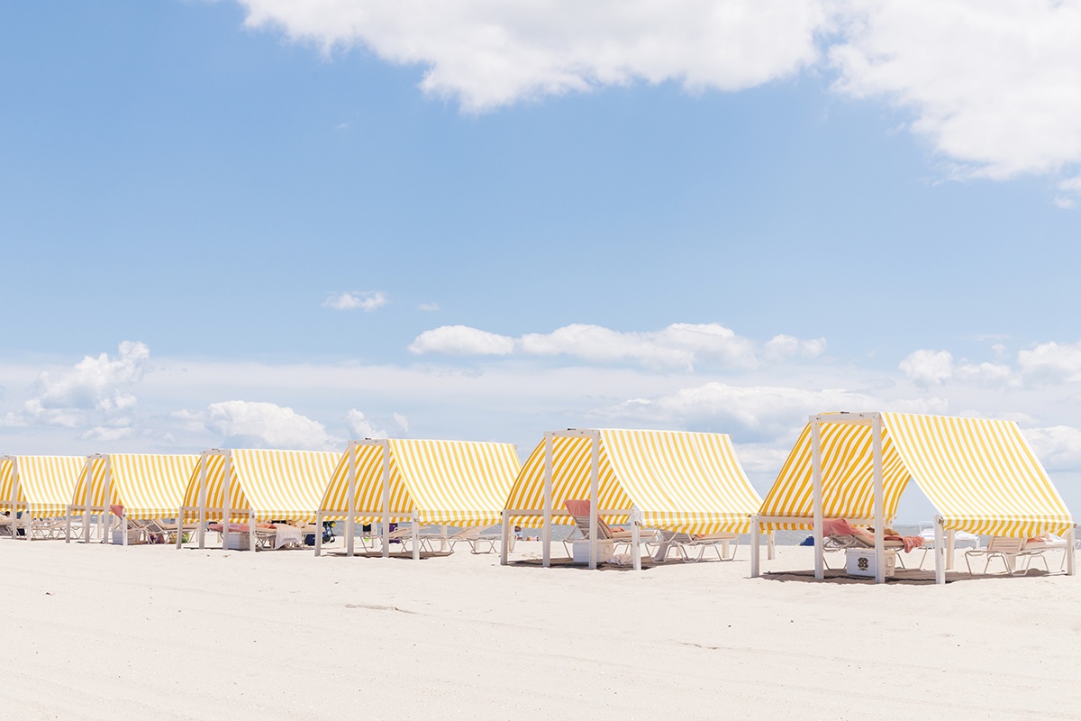 Congress Hall yellow and white beach cabanas on the beach with a blue sky