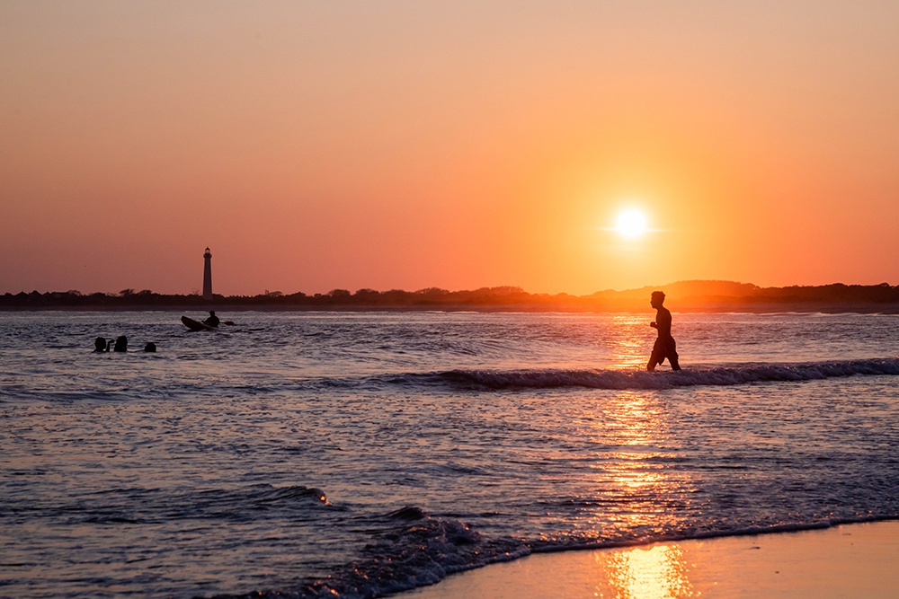 A person walking back into the ocean at sunset