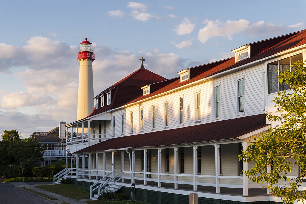 Sunlight shining on St. Mary's by the Sea and the Cape May Point Lighthouse with pink clouds in the distance