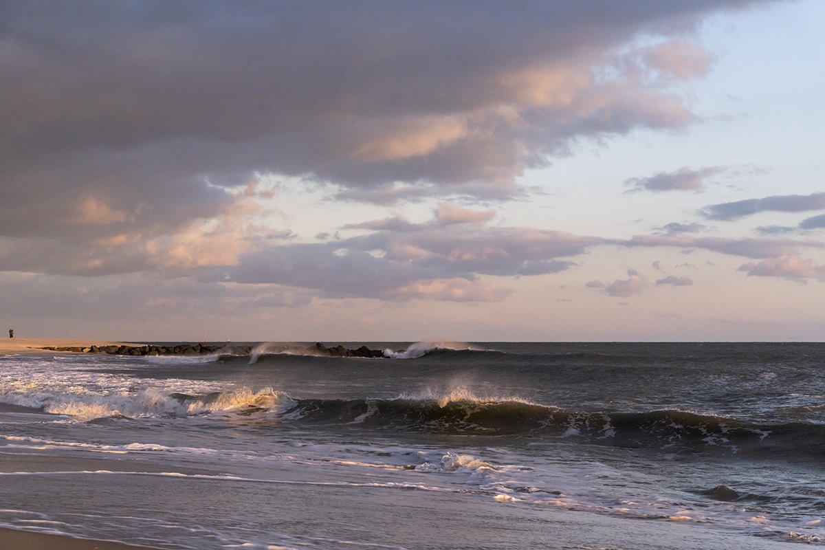 Waves crashing and foaming with pink clouds in the sky