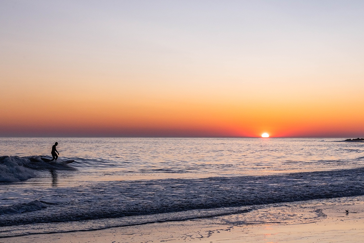 A surfer riding a wave as the sun sets