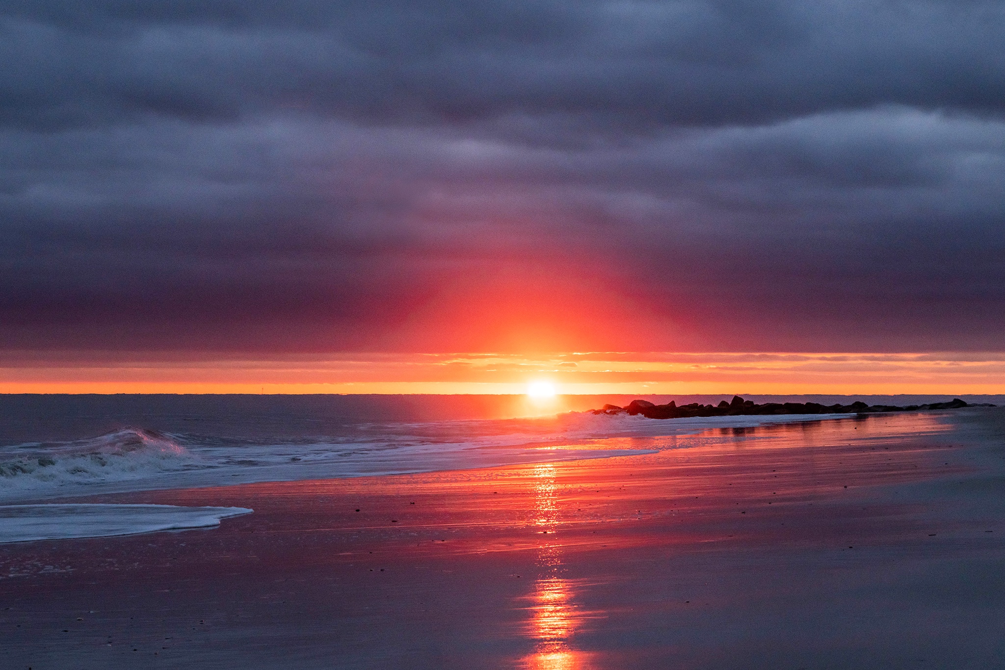 Bright spotlight sun setting at the horizon with dark clouds in the sky