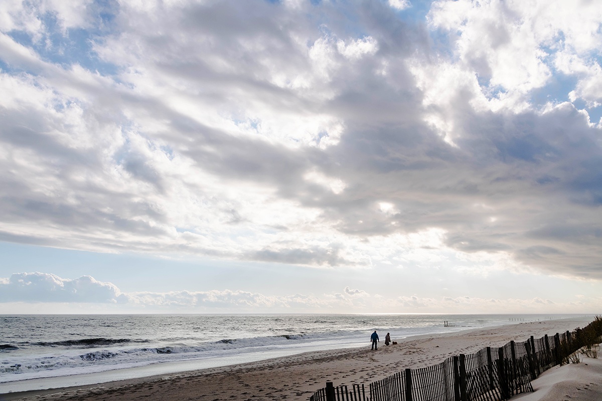 Clouds in the sky coming closer while people walk on the beach