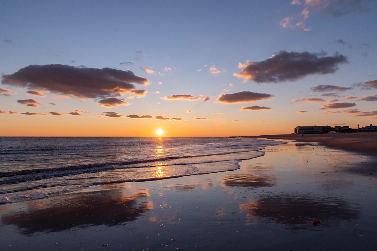 Sunset at the beach with clouds reflected in the shoreline