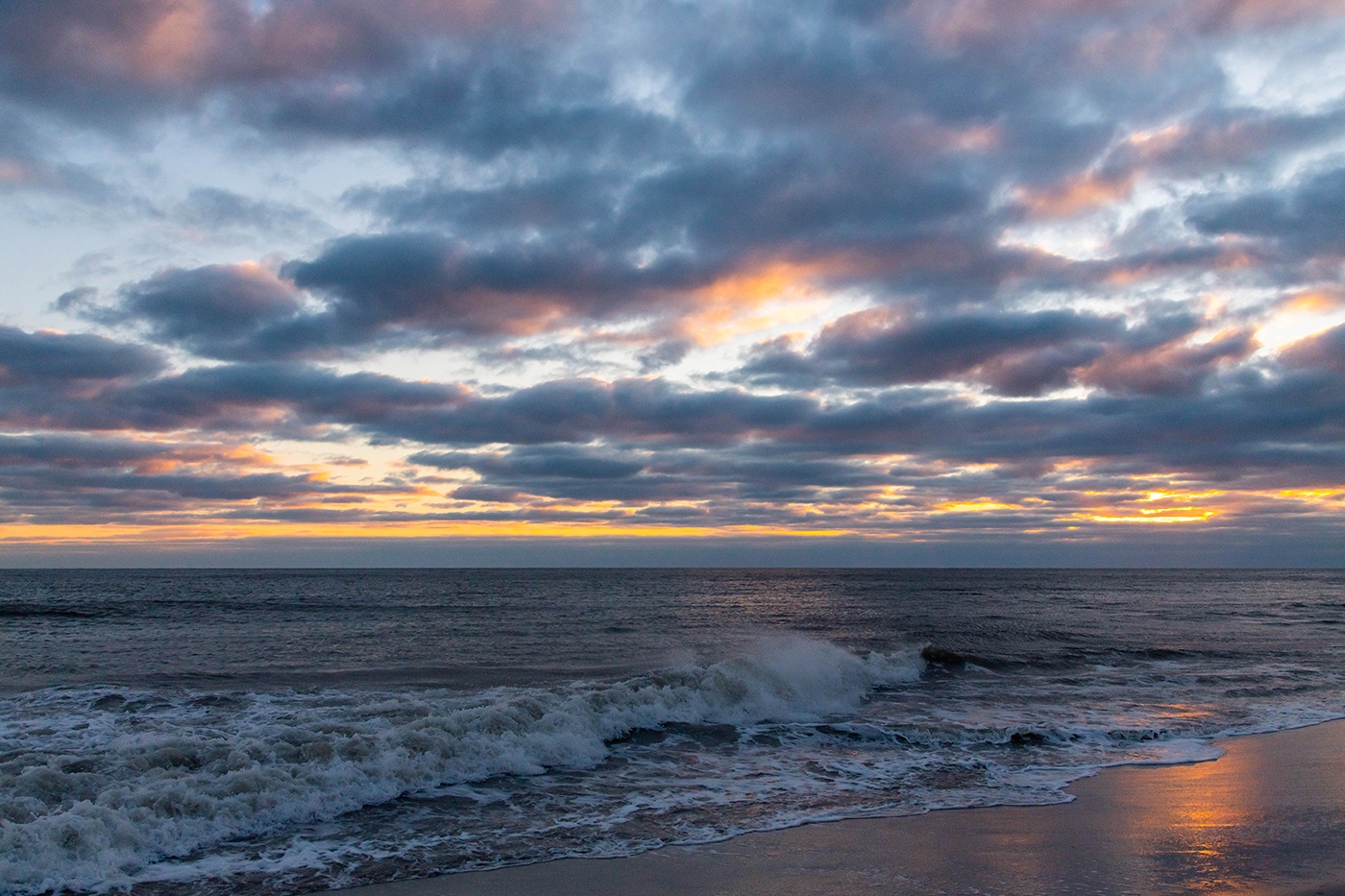 Waves crashing at sunset with clouds in the sky 