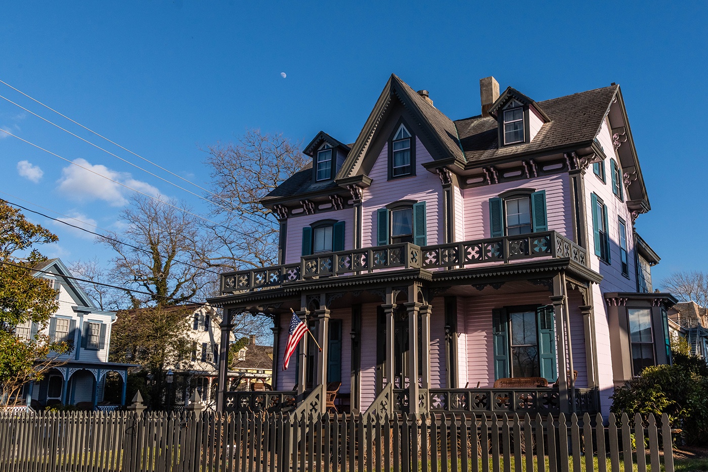 A pink and teal Victorian house on a sunny winter day with a clear blue sky