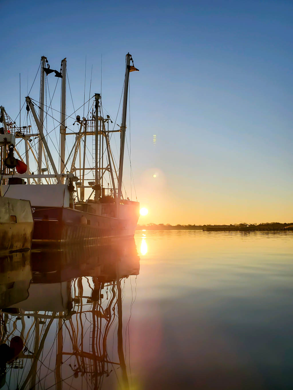 On the water looking into the sun by the fishing boats