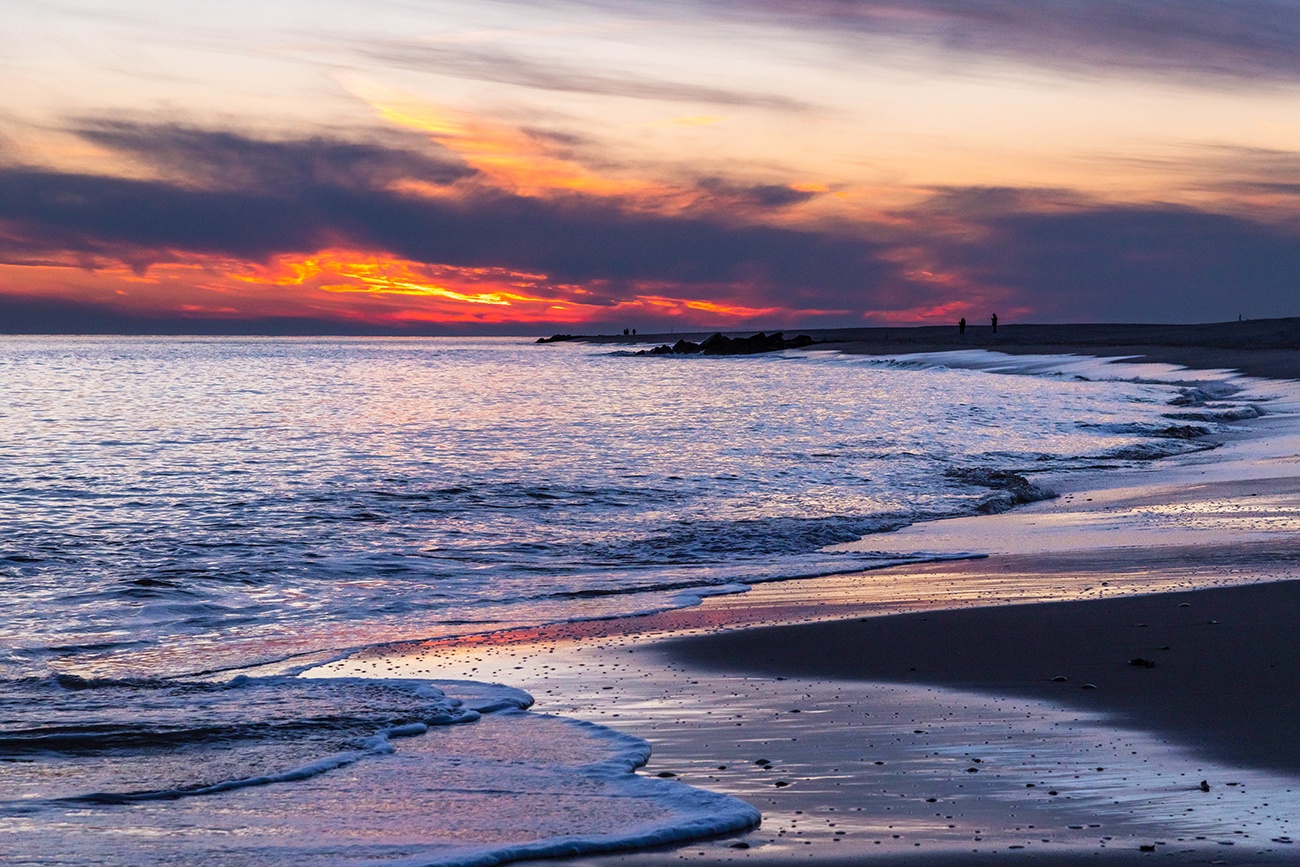 Pink and purple colored clouds at the horizon at sunset with the ocean coming in