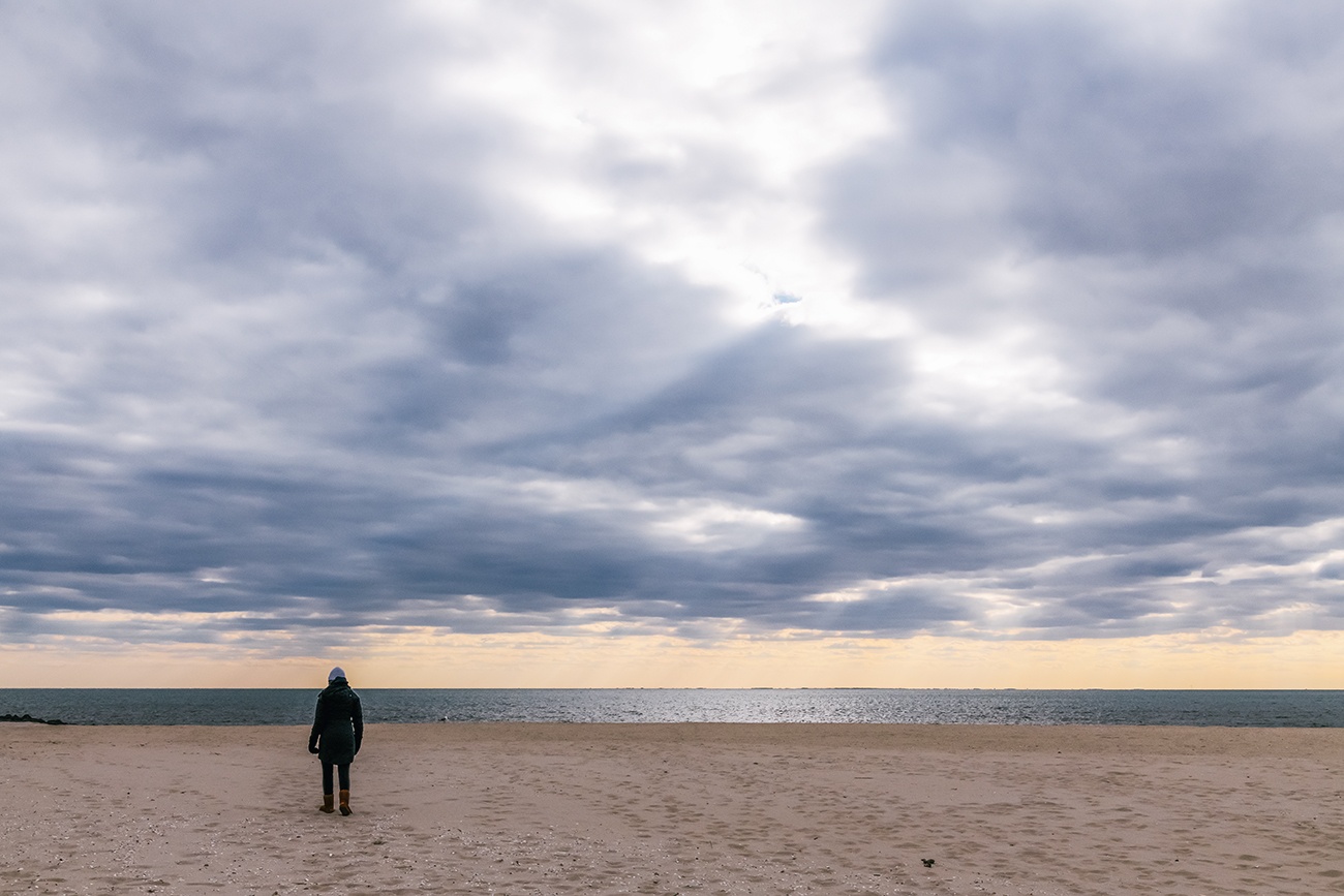 A person walking on the beach on a cloudy day