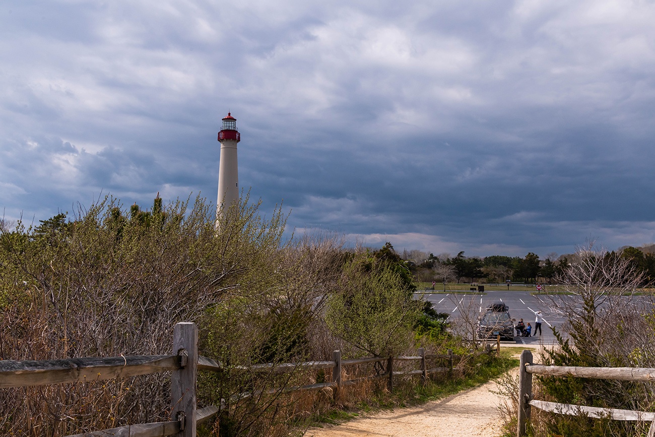 The Cape May Lighthouse on a cloudy day with a path to the beach