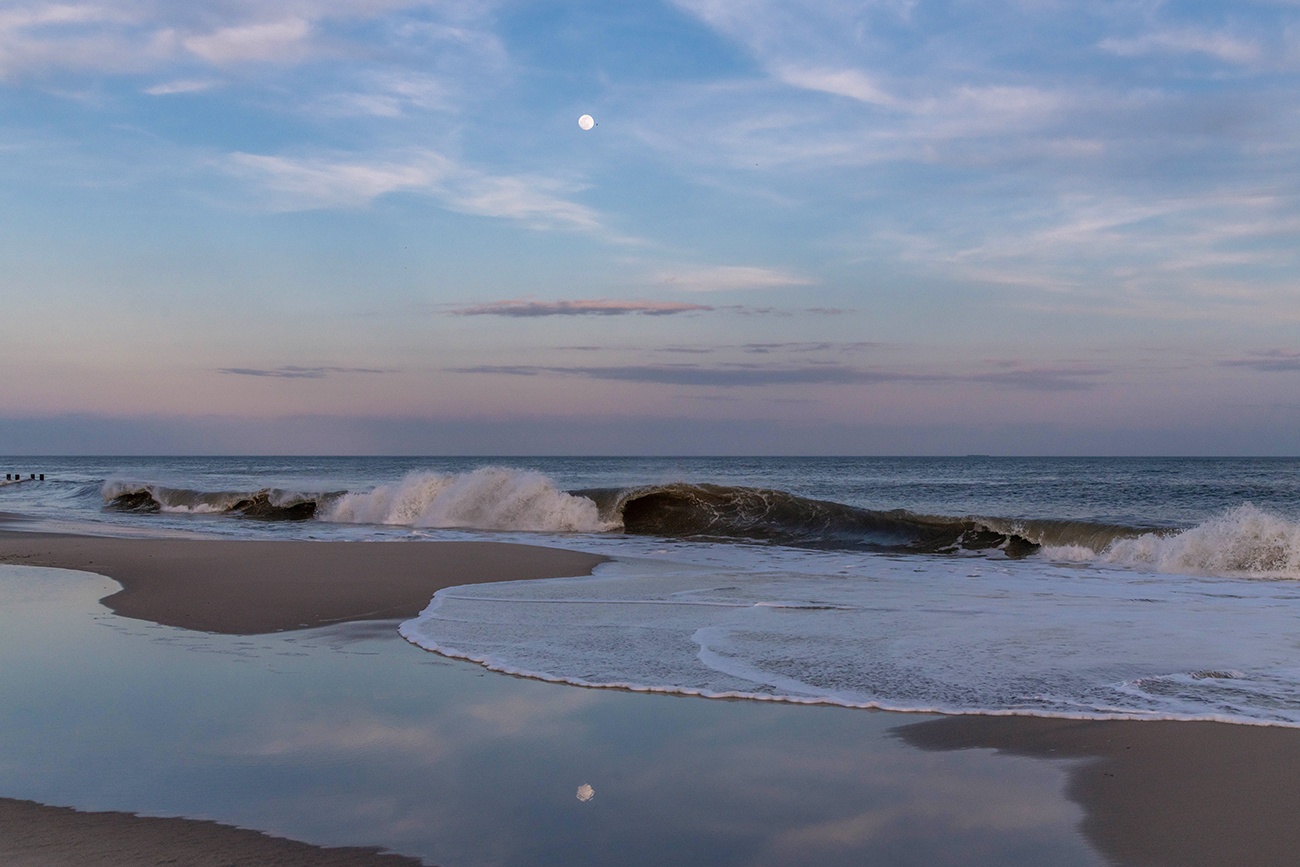 A full moon rising over the ocean and reflected in the water