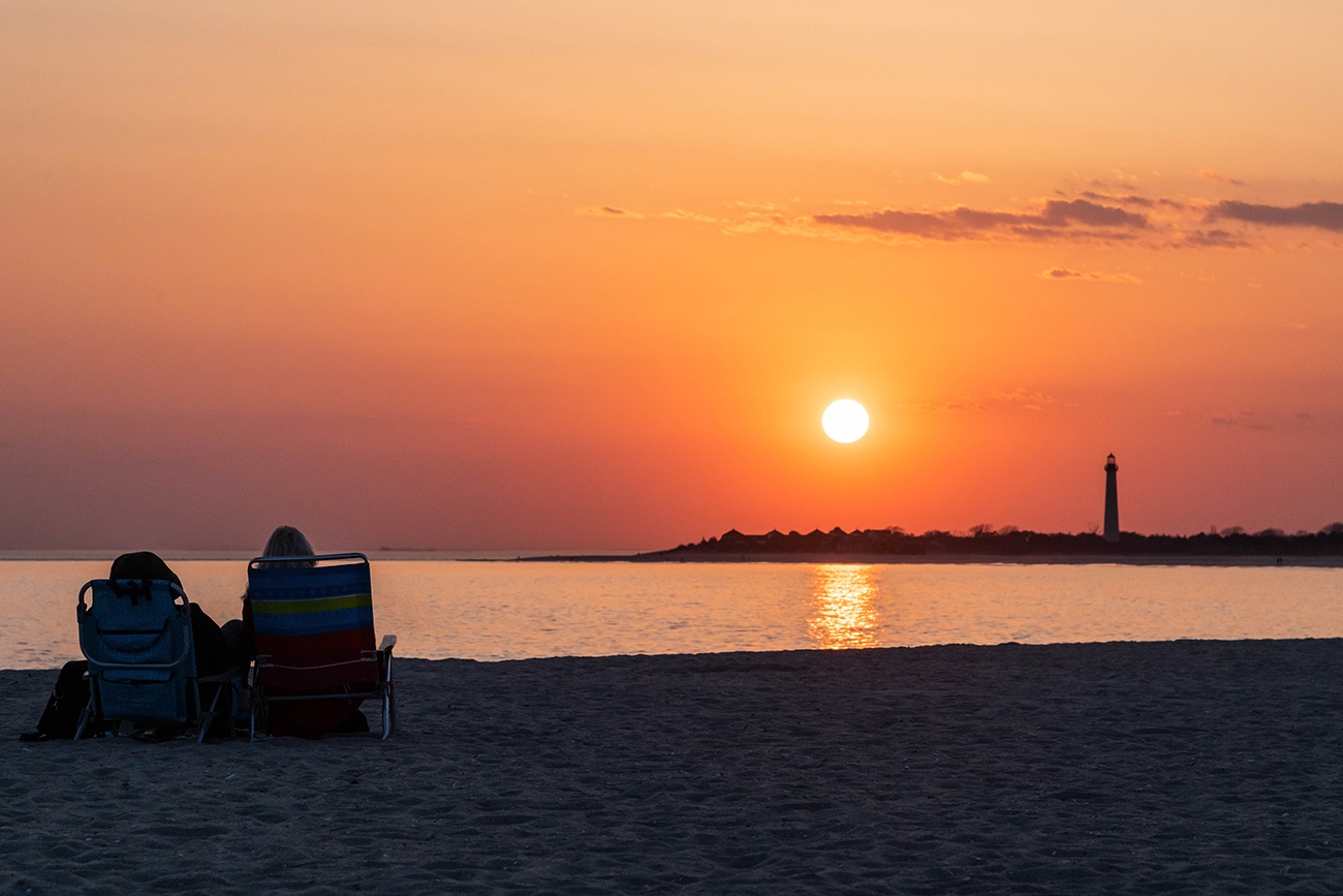 Two people sitting on the beach watching sunset