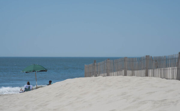 Just Past The Dunes people are sitting watching the waves.