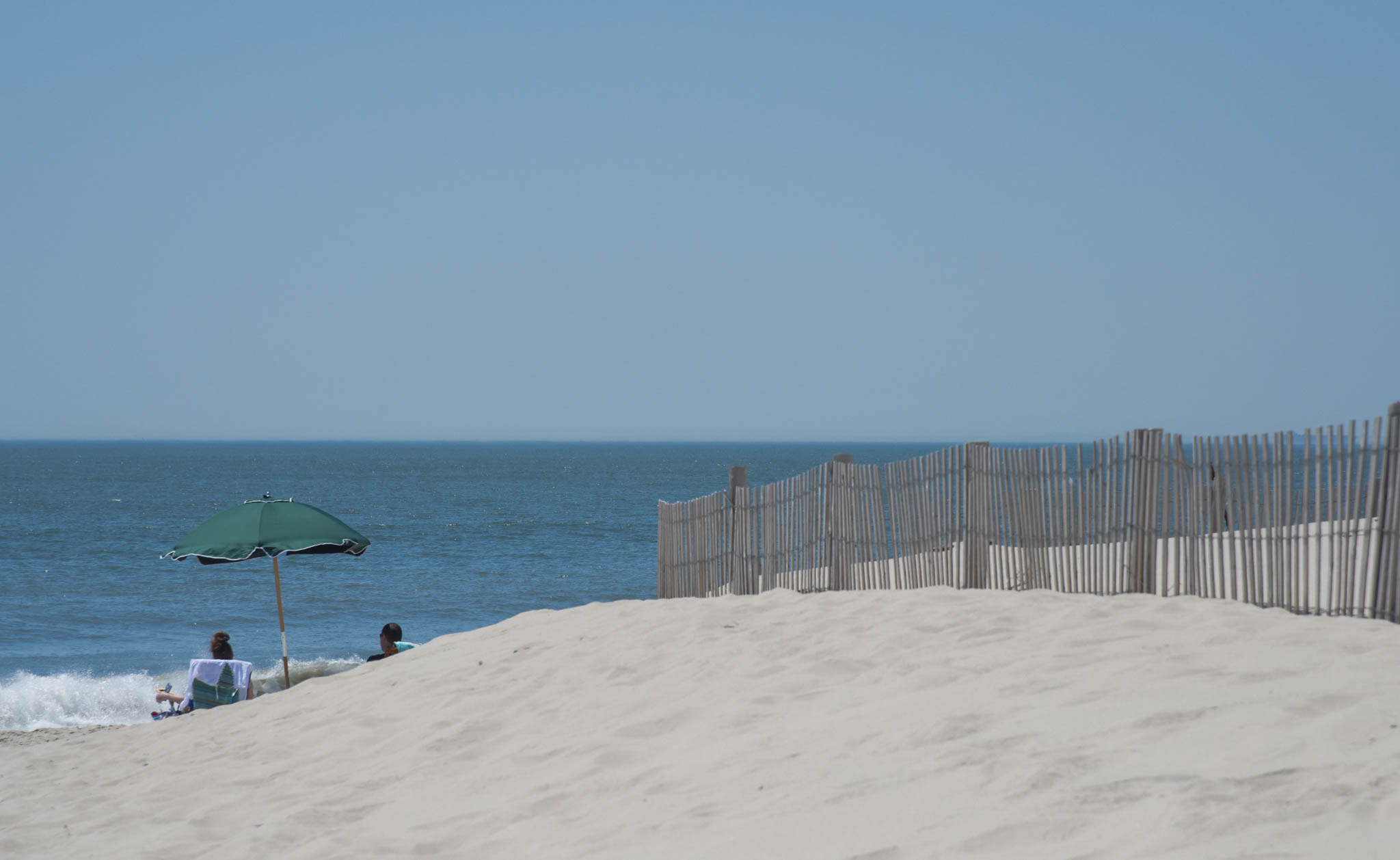 Just Past The Dunes people are sitting watching the waves.