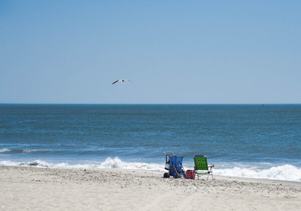 Later in the afternoon where a seagull flies by over a beach chair