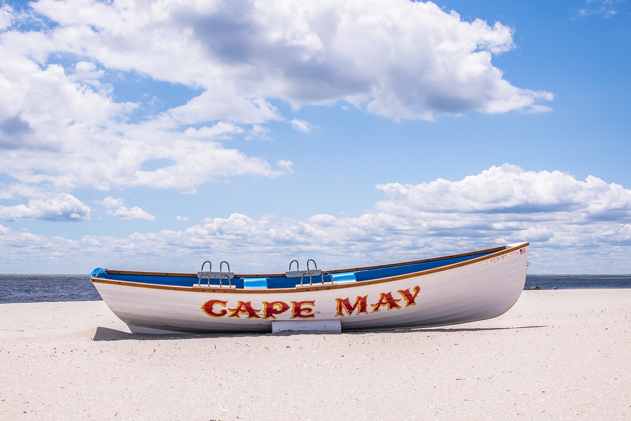 A Cape May lifeguard boat on the beach on a sunny day with blue skies and puffy white clouds