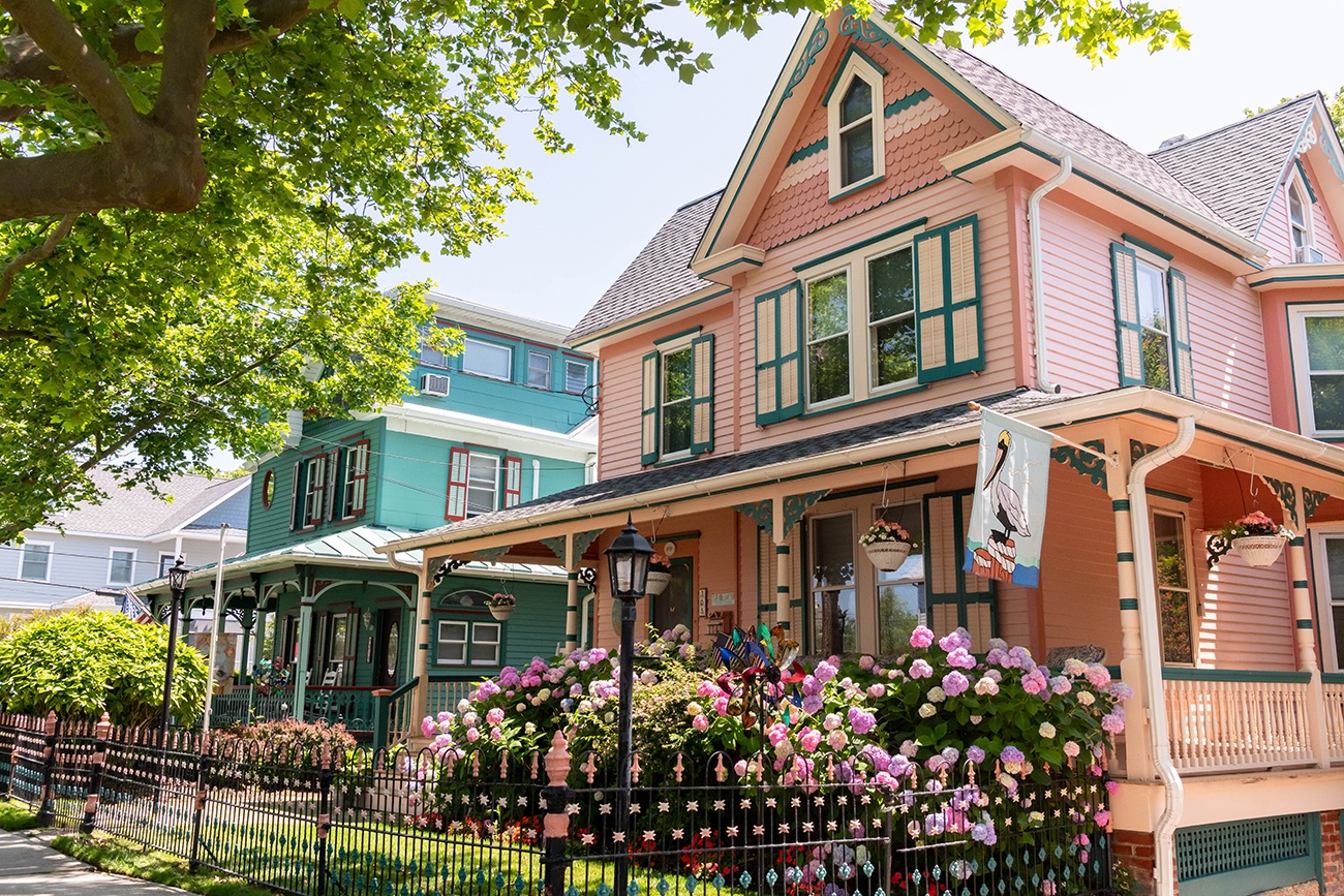 A pink Victorian house with pink and purple hydrangea on a sunny day