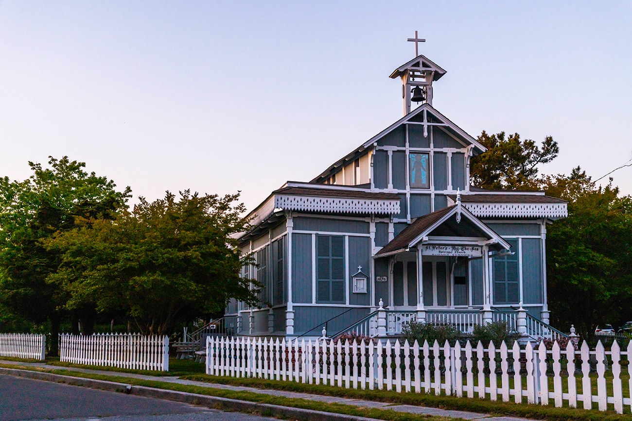 St. Peter's by the Sea, a small teal church with a white fence, at dusk