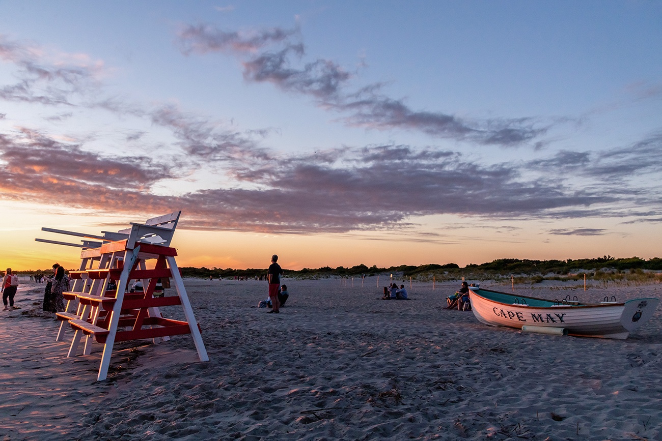 Two lifeguard stands and a Cape May boat shining in sunset light on the beach