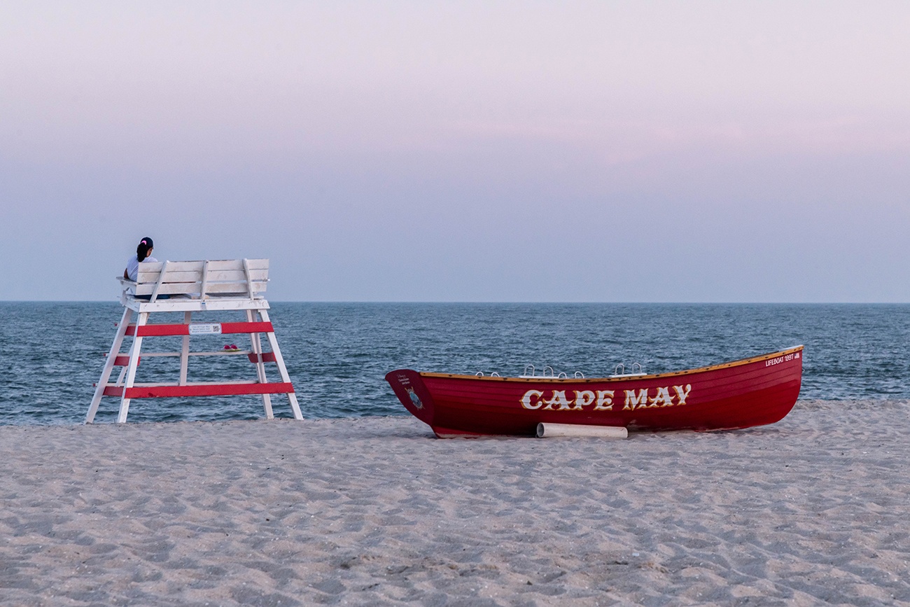 A lifeguard stand and Cape May red lifeguard boat at the beach with pink skies 