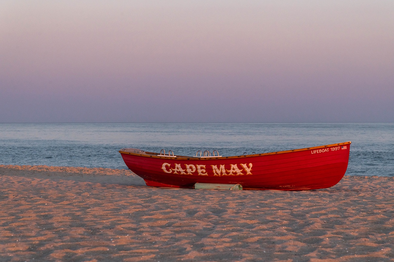 A red Cape May lifeguard boat on the beach at sunset