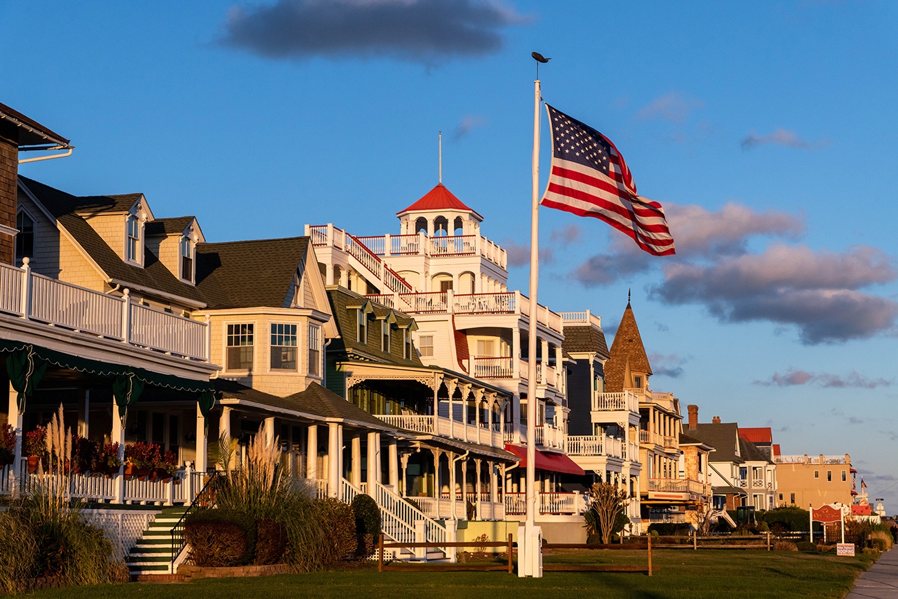 Sun shining on Victorian houses at sunset with an American Flag blowing in the wind