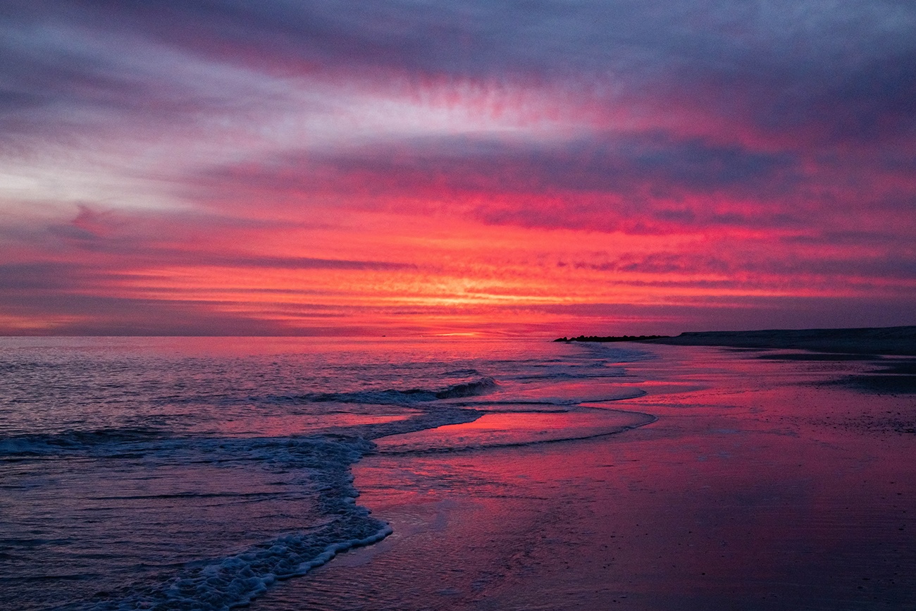 Pink, purple, and orange clouds in the sky at sunset at the beach