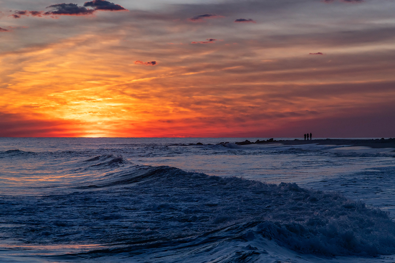 Orange and reds in the sky at sunset as waves crash in the ocean
