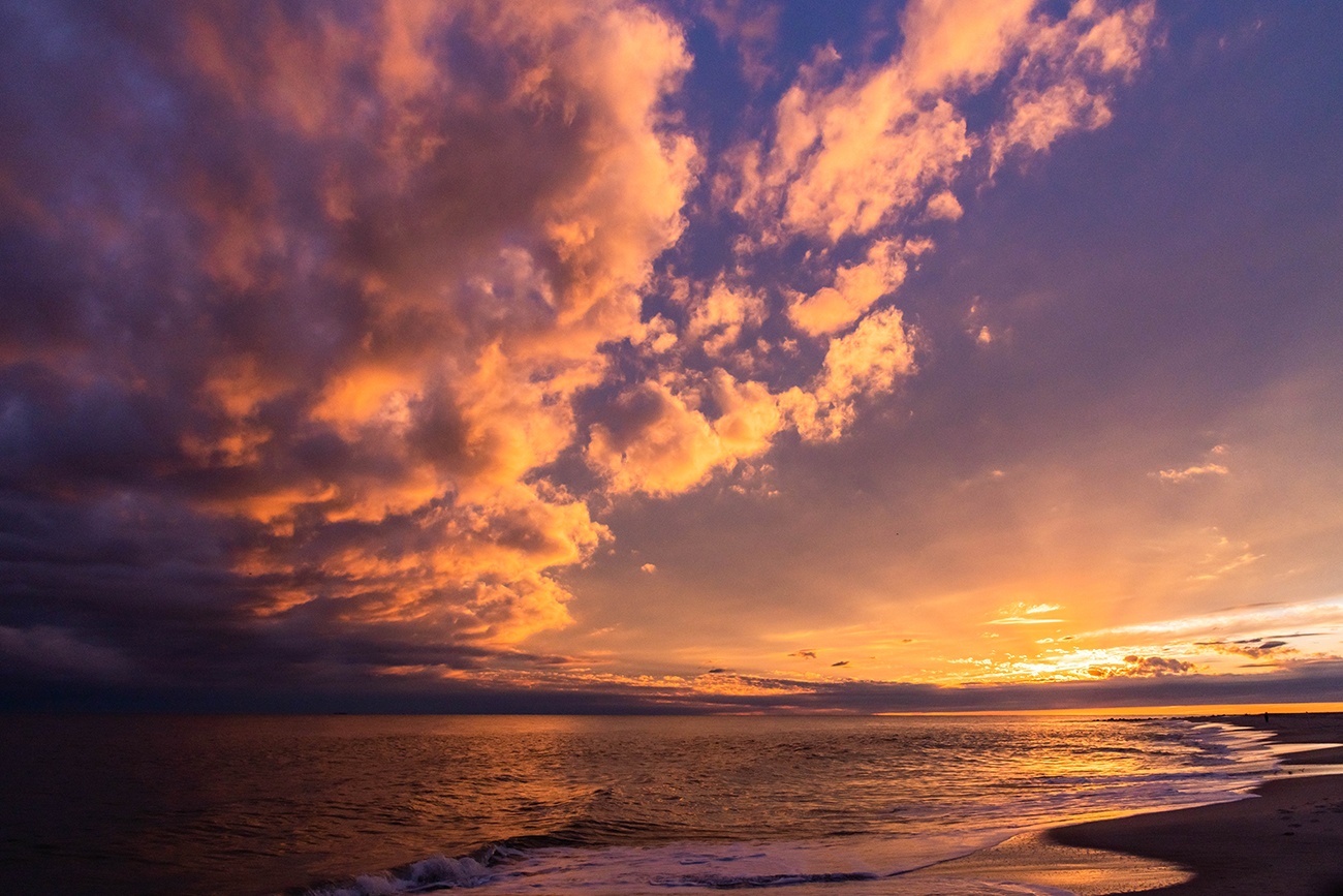 Pink, orange, and blue colorful clouds in the sky at sunset at the beach