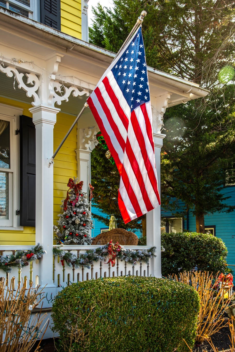 American Flag on the front of a house with Christmas decor on the porch