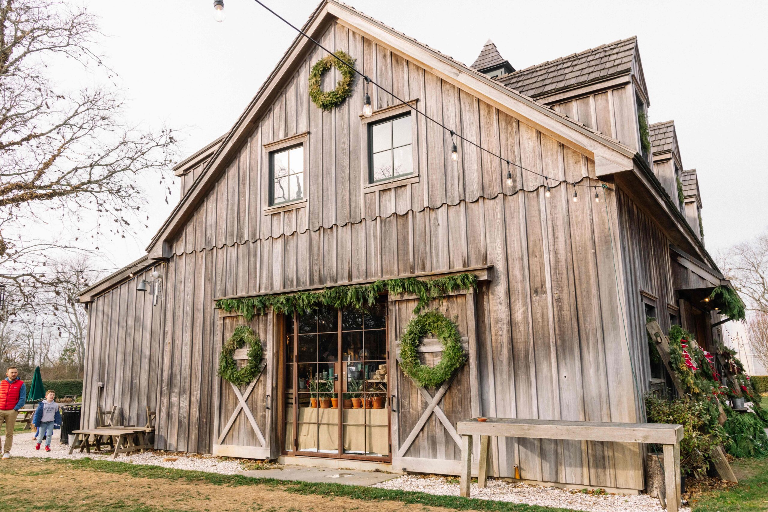 Beach Plum Farmhouse with green wreaths hung on the doors and lights strung up