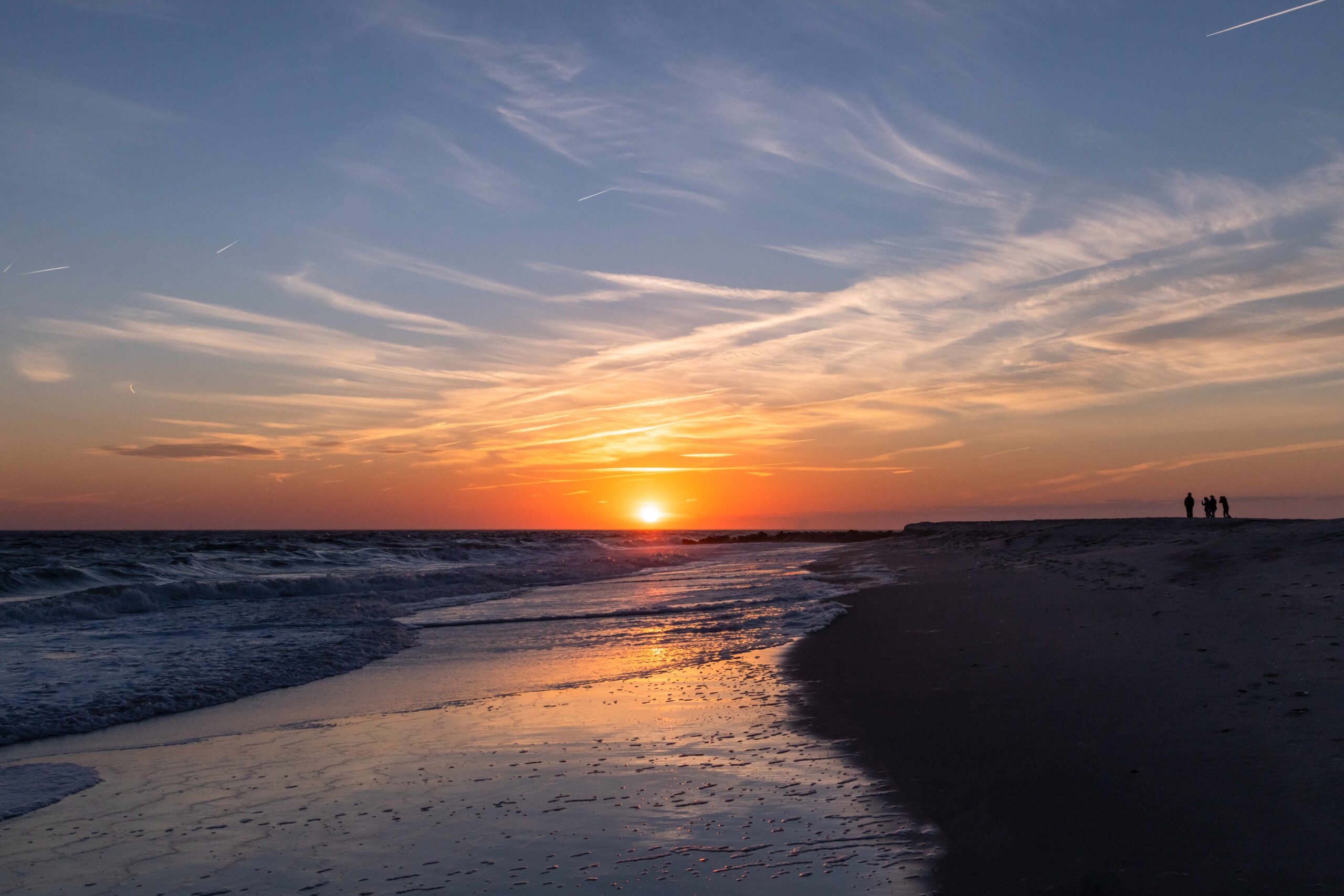 People at the horizon on the beach watching sunset 