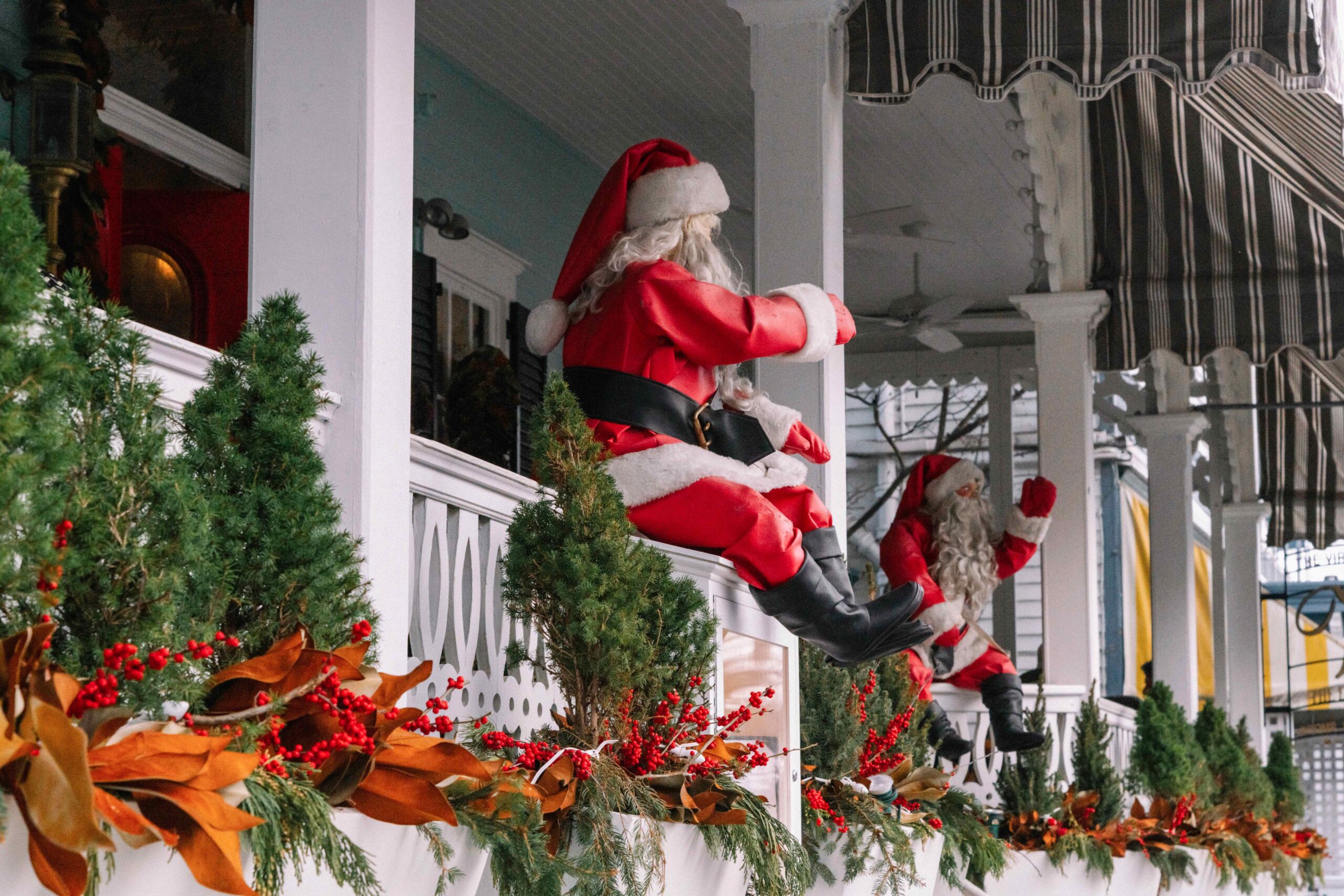 Two Santa Christmas decorations sitting on the porch at Virginia Hotel with evergreen and holy