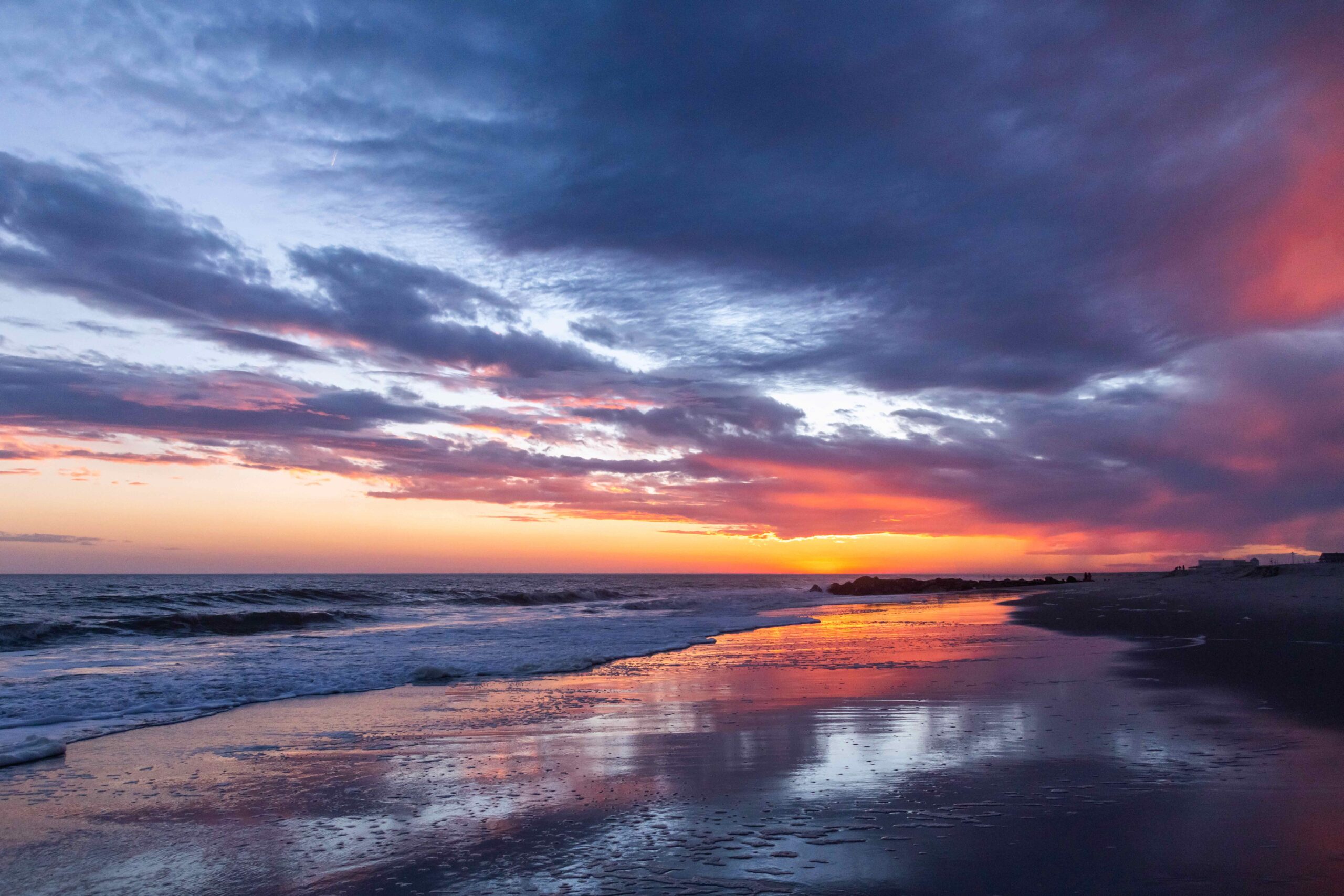 Pink and purple clouds in the sky reflected in the sand at sunset on the beach 