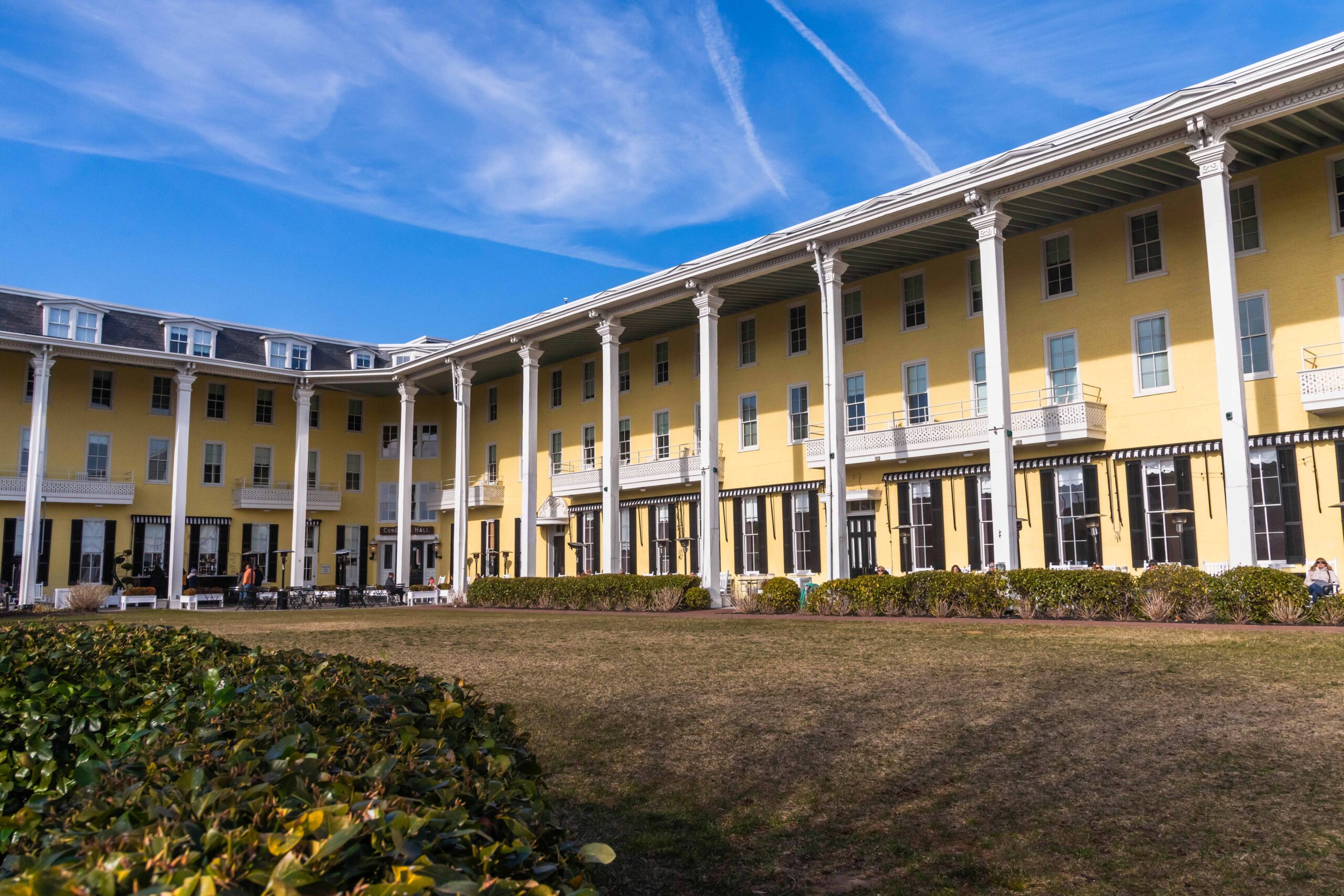 A wide view of Congress Hall with the front lawn and a clear blue sky 