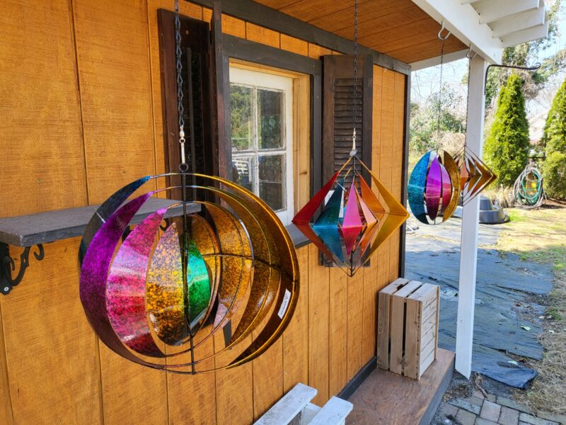 Four wind sculptures hanging from an overhang