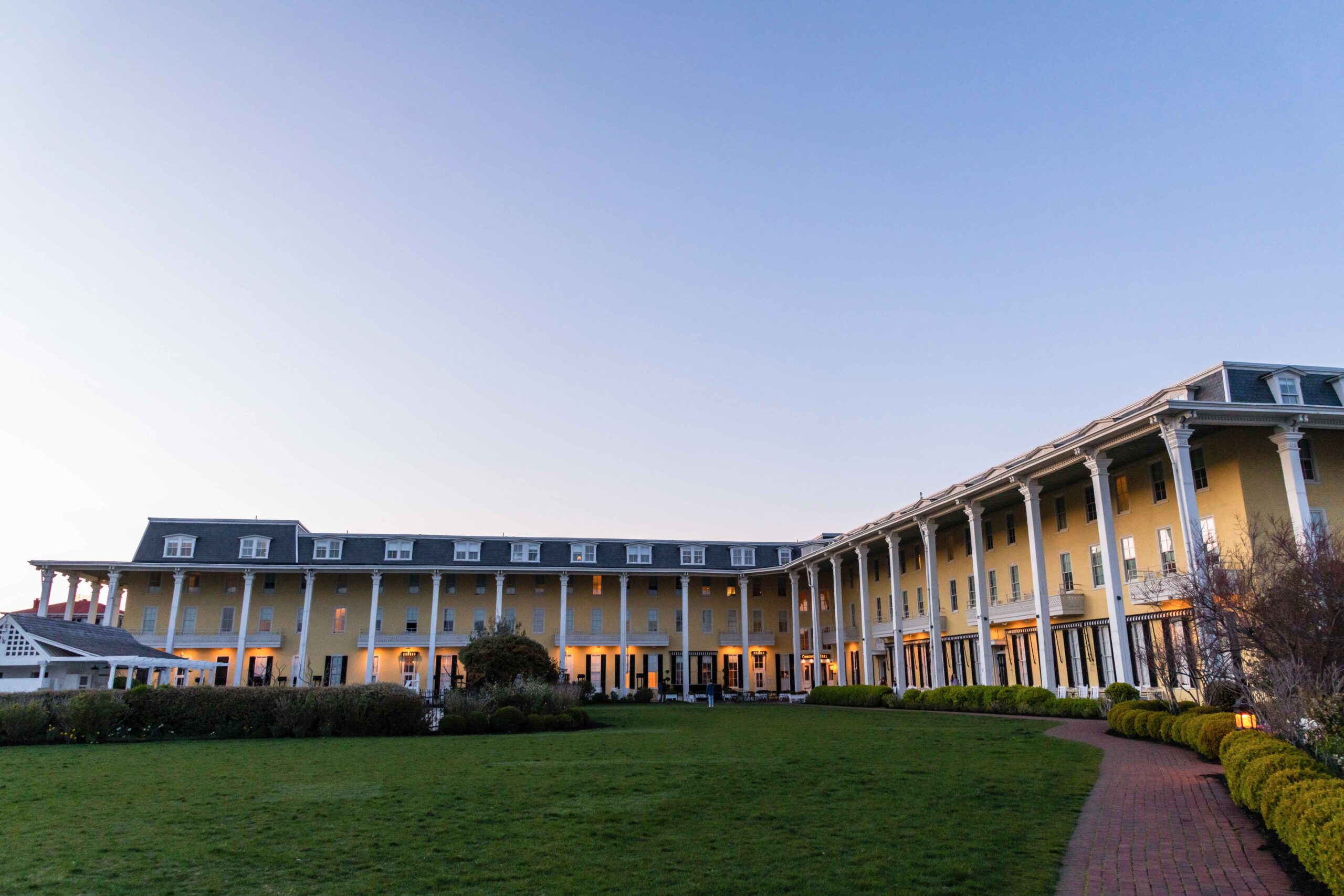 A wide view of Congress Hall and the front lawn during the early evening with a clear blue sky