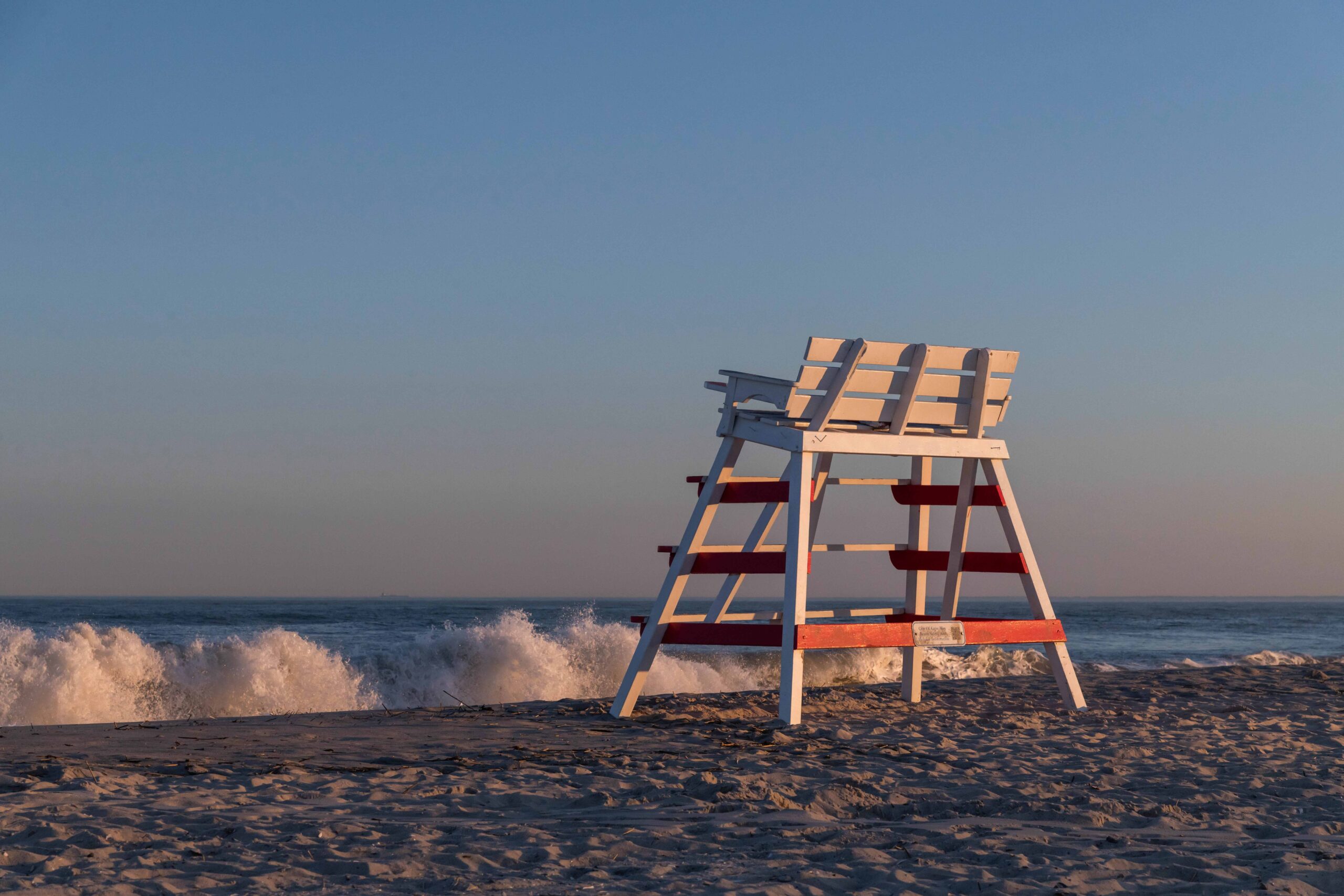 A lifeguard stand on the beach with waves crashing in the background