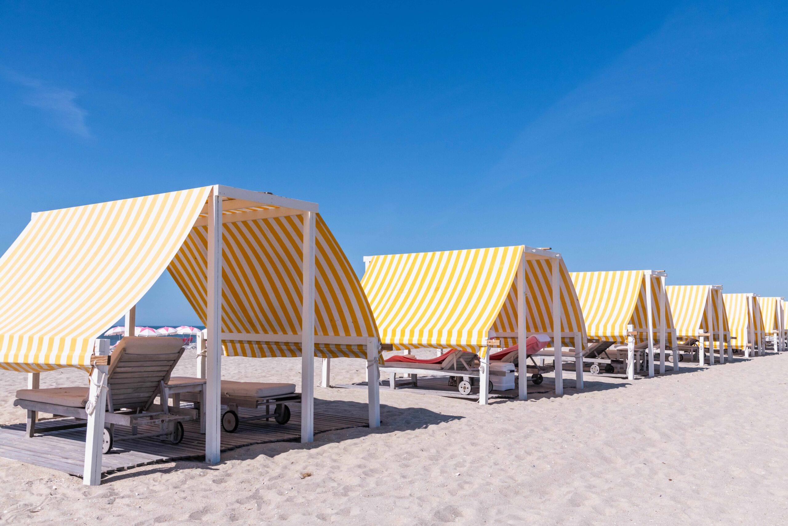 Yellow and white beach cabanas from Congress Hall on the beach with a clear blue sky
