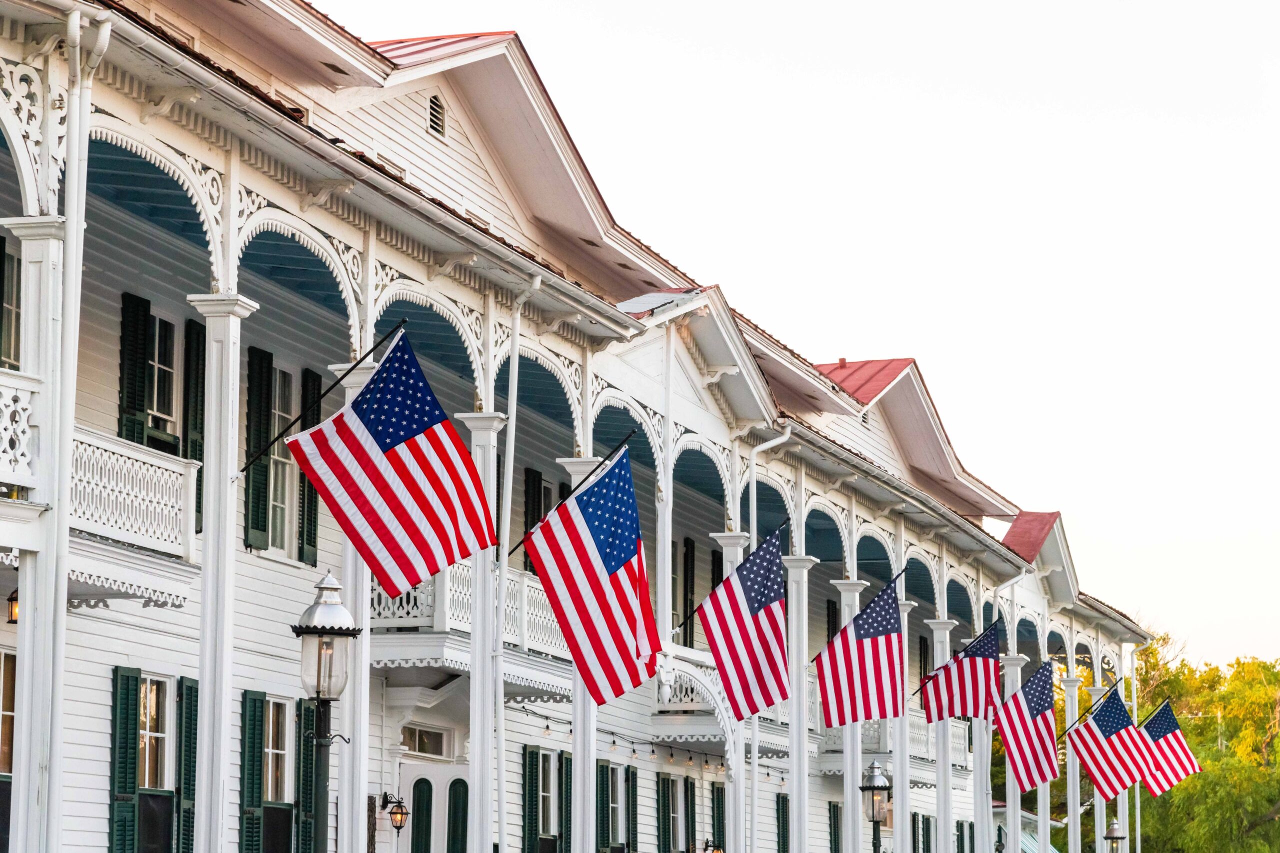 A row of American flags hanging from banisters at the Chalfont Hotel on a sunny afternoon