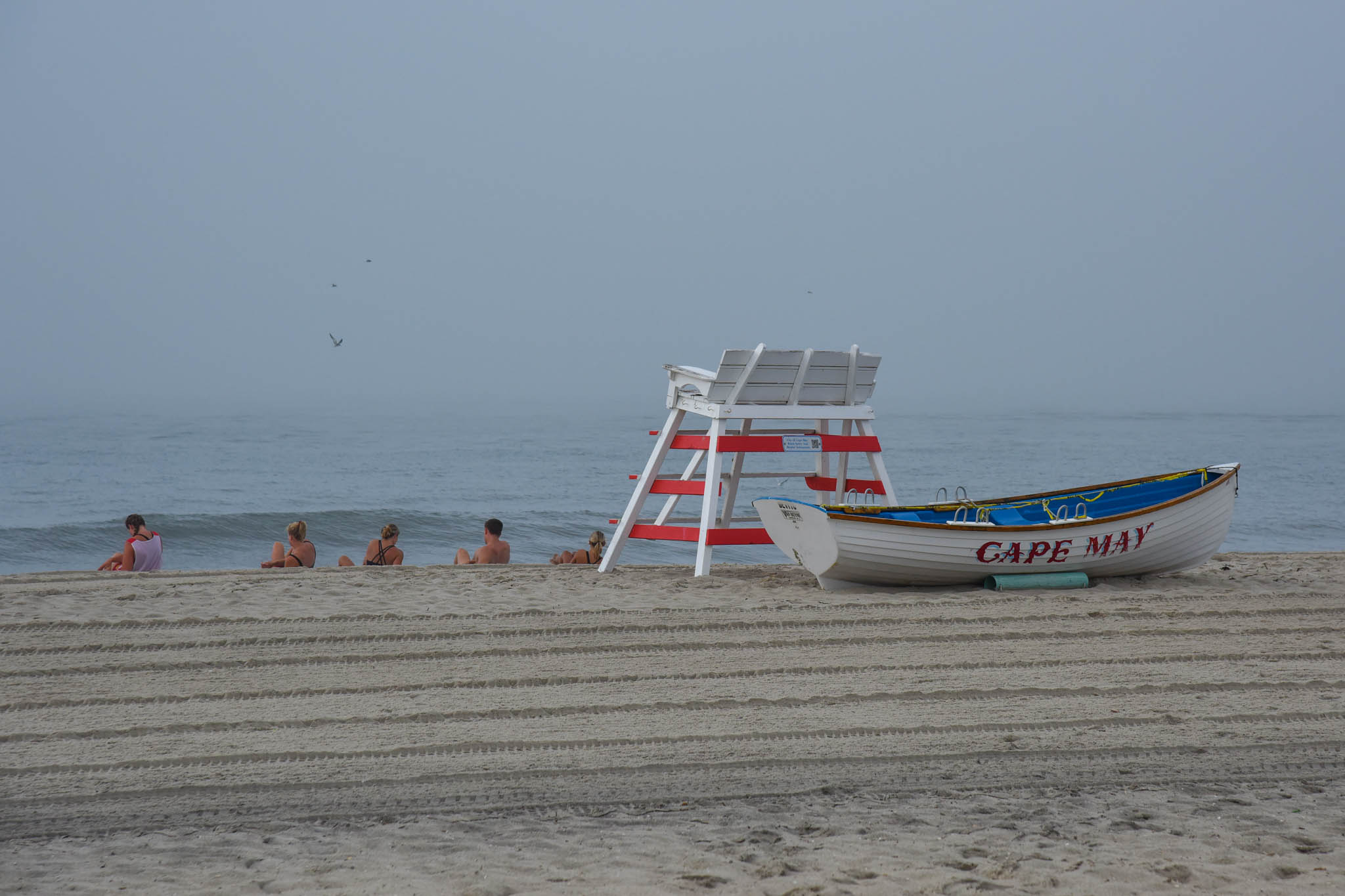 People working out in front of the Lifeguard stand and Boat on the beach
