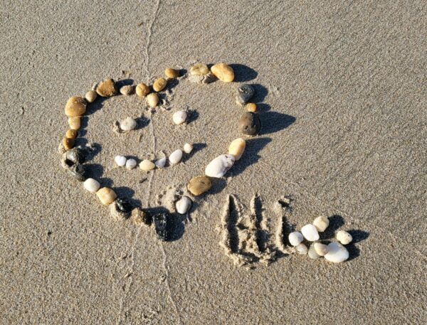 Stones shaped as a heart with Hi spelled out in the sand